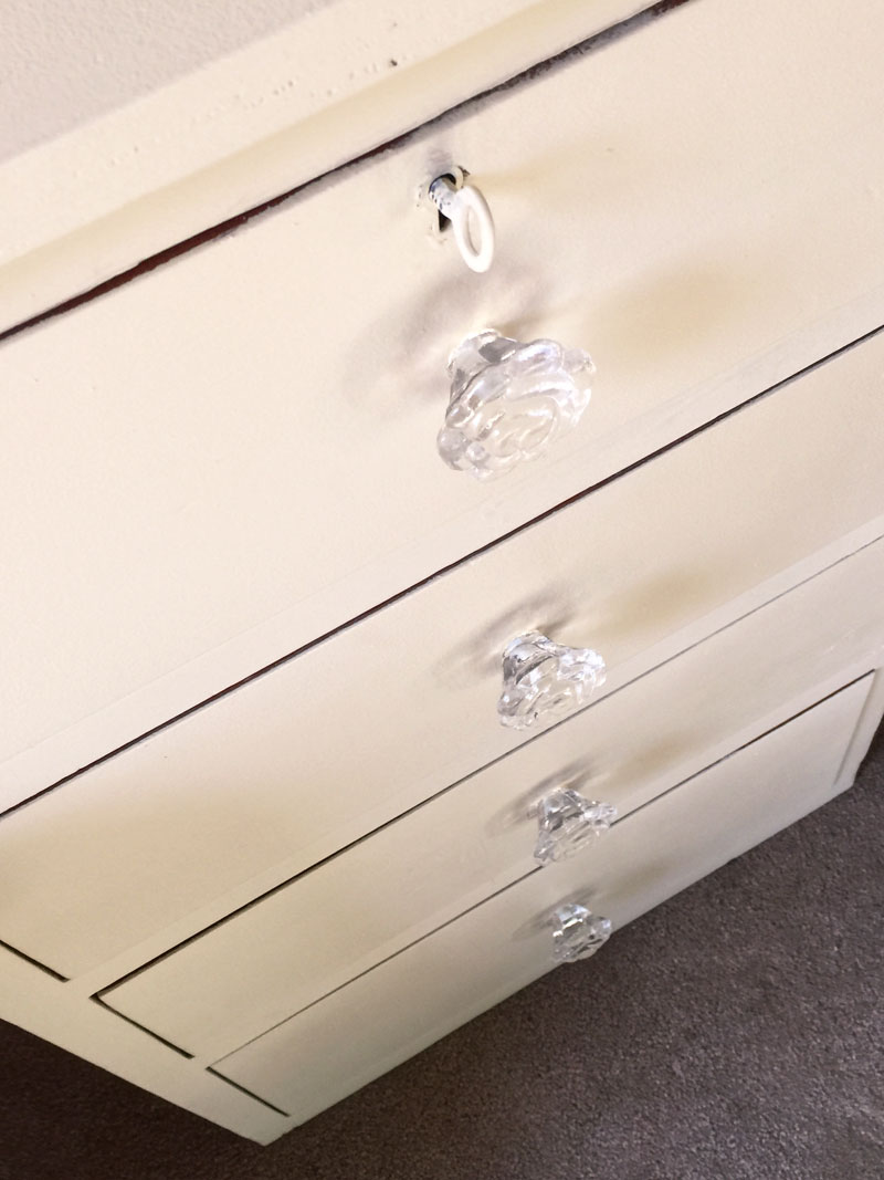Glass knobs accent the drawer fronts of painted small chest of drawers