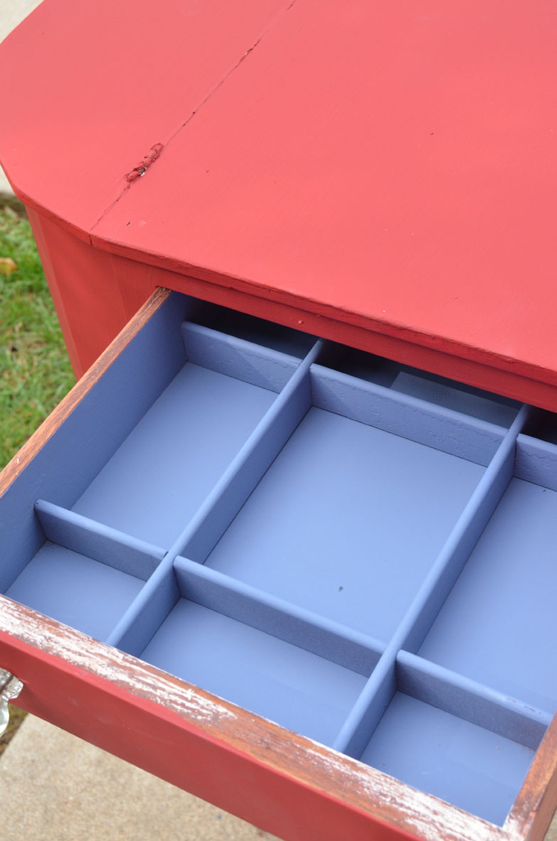 sewing cabinet painted red on the outside and blue on the inside of the drawers