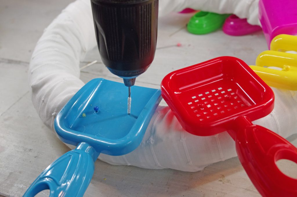 attach sand toys by drilling small holes and pushing pins through holes and into the wreath form